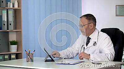 Doctor keeping patients medical records on tablet, modern hospital database Stock Photo