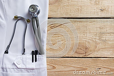 Doctor lab white coat pocket with pen, stethoscope, close-up shot on vintage wooden background. Copy space Stock Photo