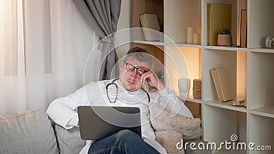 Doctor late work sleepy man couch laptop evening Stock Photo