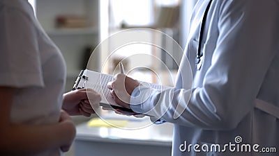 Doctor listening female complaint on stomach ache and writing down notes, clinic Stock Photo