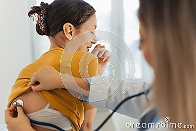 Doctor listening girl& x27;s breathing, heartbeats using a stethoscope. Teenage girl visiting paediatrician for annual Stock Photo