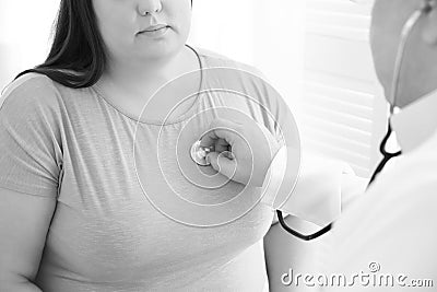 Doctor listening to overweight patient`s heartbeat with stethoscope in clinic Stock Photo