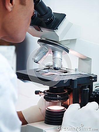 Doctor looking into microscope Stock Photo