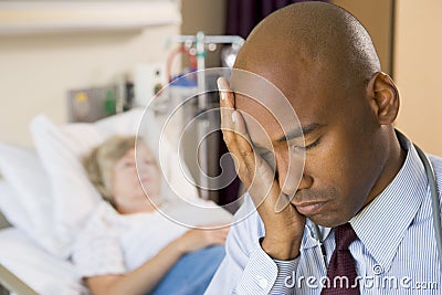 Doctor Looking Tired In Hospital Room Stock Photo