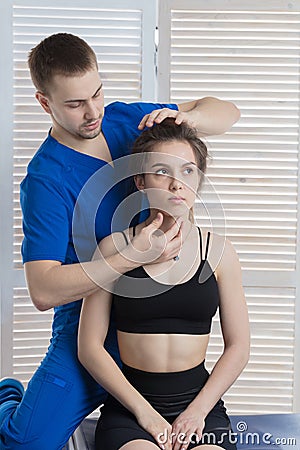 The doctor makes a diagnosis of the head and cervical spine of a young girl. Massage and manual therapy Stock Photo