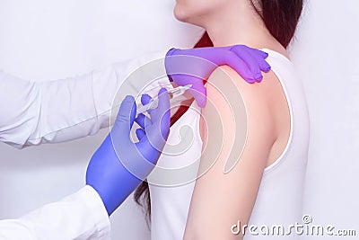 Doctor makes an injection of blockade of chondroprotector and anti-inflammatory drug in the girl`s sore shoulder, white backgroun Stock Photo