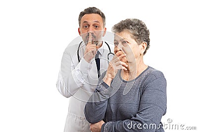 Doctor making shush gesture behind patient Stock Photo