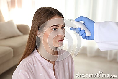 Doctor measuring patient`s temperature with non contact infrared thermometer at home, closeup Stock Photo