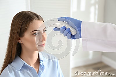 Doctor measuring patient`s temperature with non contact infrared thermometer in office Stock Photo
