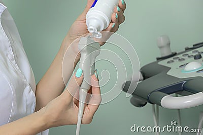 a doctor in a medical gown applies gel to an ultrasound machine for human organs. Stock Photo