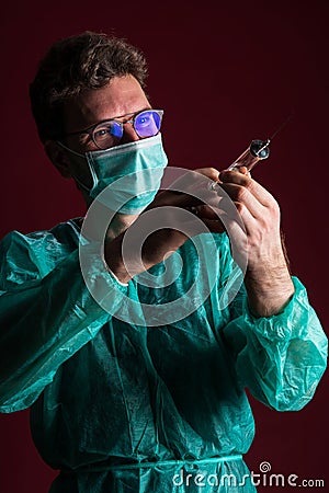 Doctor in medical mask make protective injection. Nurse in glasses prepare syringe. Stock Photo