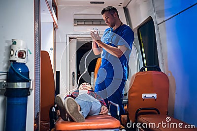 Doctor in uniform puts oxygen mask on woman lying on stretcher in the ambulance car Stock Photo