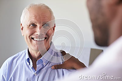 Doctor Meeting With Mature Male Patient In Exam Room Stock Photo