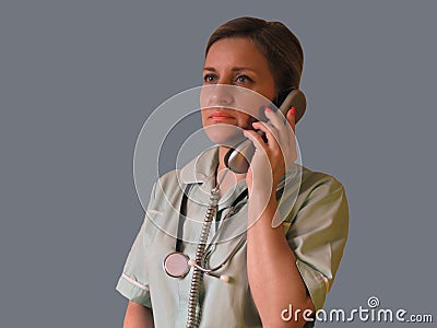 Doctor or nurse call by phone. Woman in uniform with handset and stethoscope around neck speaks Stock Photo
