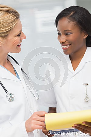 Doctor and nurse going over file together smiling at each other Stock Photo