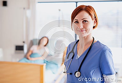 A doctor or nurse standing in hospital room, looking at camera. Stock Photo