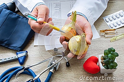 Doctor nutritionist during consultation held in his hand and shows patient onion bulb. Counseling and explanation of use of onion Stock Photo