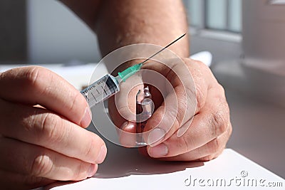 A doctor opened ampoule and hold it in one hand and a syringe in another. Stock Photo