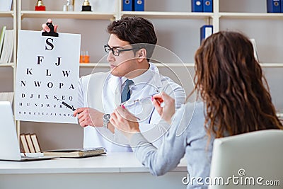 The doctor optician with letter chart conducting an eye test check Stock Photo