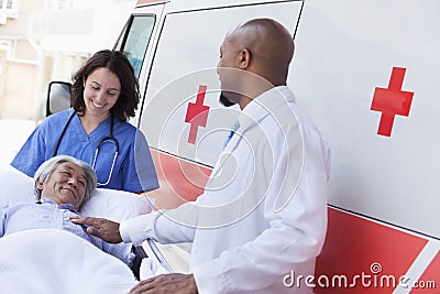 Doctor and paramedic wheeling in a elderly patient on a stretcher in front of an ambulance Stock Photo