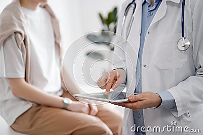 Doctor and patient in clinic. Friendly physician using tablet computer near a young woman. Medicine concept Stock Photo
