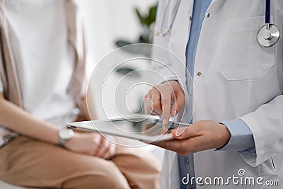 Doctor and patient in clinic. Friendly physician using tablet computer near a young woman. Medicine concept Stock Photo