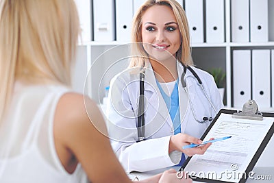 Doctor and patient discussing something while physician pointing into medical history form at clipboard Stock Photo