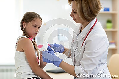 Doctor pediatrician holding syringe with injection vaccination. Girl is afraid. Stock Photo