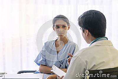 Doctor with pen and stethoscope sitting in office while talking about problem health patient woman fell friendly Stock Photo