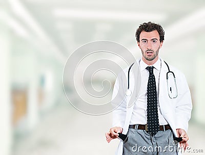 Doctor penniless showing empty pockets standing in hospital hallway Stock Photo