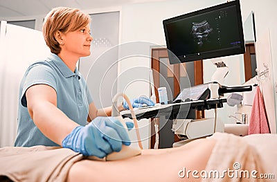 Doctor performing ultrasound procedure in modern clinic. Stock Photo