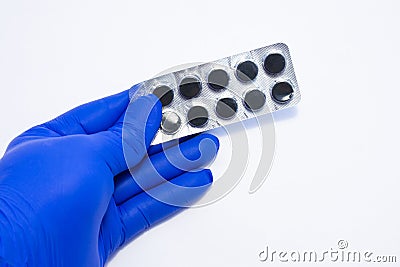 Doctor, pharmacist or scientist holding blister pack with black pills that contain activated carbon. Concept picture for treating Stock Photo