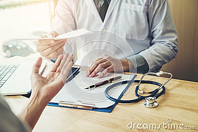 Doctor or physician writing diagnosis and giving a medical prescription to female Patient Stock Photo