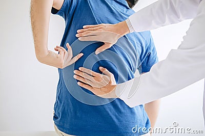 Doctor physiotherapist treating lower back pain patient after while giving exercising treatment on stretching in the clinic, Stock Photo