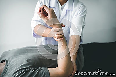 Doctor or Physiotherapist working examining treating injured arm of athlete male patient, stretching and exercise, Doing the Stock Photo