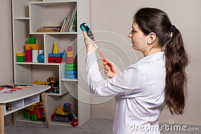 The doctor picks up from the bottle a sprinkle of cough and temperature for children in a measuring tube plastic syringe Stock Photo