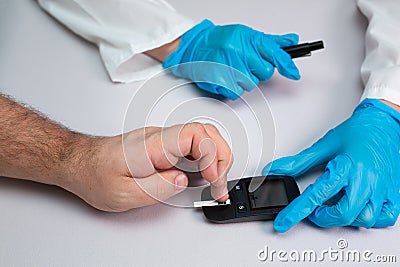 Doctor piercing patients finger with lancet in clinic closeup. Blood glucose control concept Stock Photo