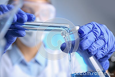 Doctor pouring blue liquid into flask. Laboratory analysis Stock Photo