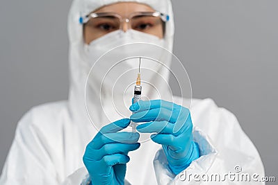 Doctor in PPE suit holding syringe with Coronavirus Covid-19 vaccine for injection test Stock Photo