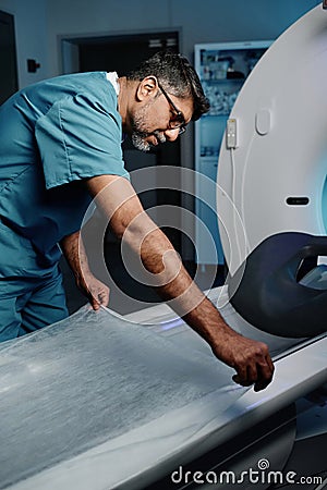 Doctor Preparing CT Scanner Bed For Next Patient Stock Photo