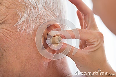 Doctor Putting Hearing Aid In Patient`s Ear Stock Photo