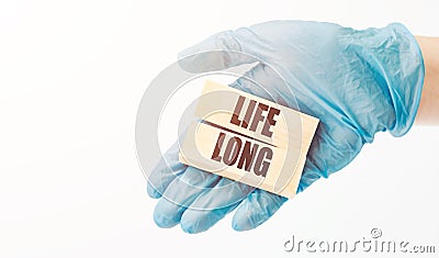 Doctor's hand in blue glove shows the wooden cubes with text LIFE LONG. Medical concept Stock Photo