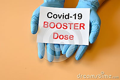 The doctor`s hands hold a paper with text `Covid-19 Booster Dose`. Concept of combating the COVID-19 and new variants virus wit Stock Photo