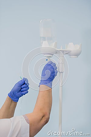 Doctor`s hands and infusion drip in hospital on blurred background Stock Photo