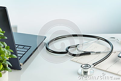 Doctor's office desk with laptop, cardiogram, tonometer and stethoscope Stock Photo