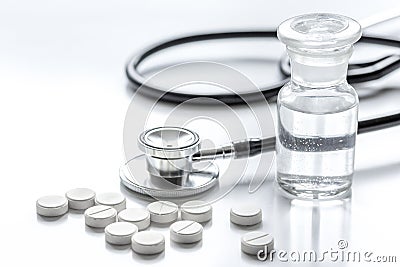 Doctor`s office table with pills, glass bottles and stethoscope white background Stock Photo