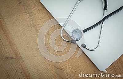 doctor`s stethoscope and laptop computer on wooden background Stock Photo