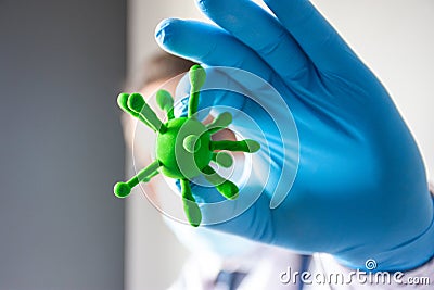 Doctor or scientist hold in hand in medical glove three-dimensional model of virus - coronavirus COVID-19 in foreground of photo c Stock Photo