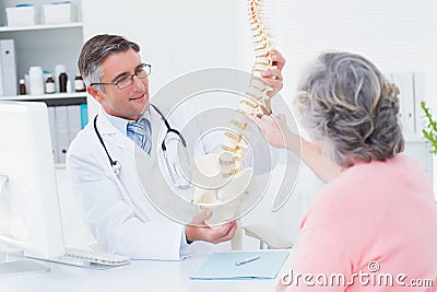 Doctor showing anatomical spine while patient touching it Stock Photo