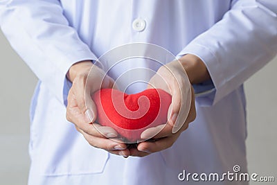 Doctor showing compassion and support holding red heart onto his chest in his coat. Stock Photo